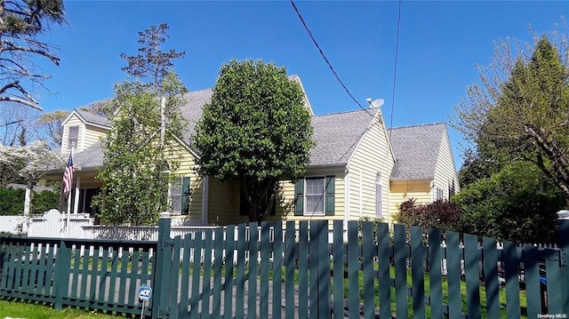 view of front of home with roof with shingles and a fenced front yard