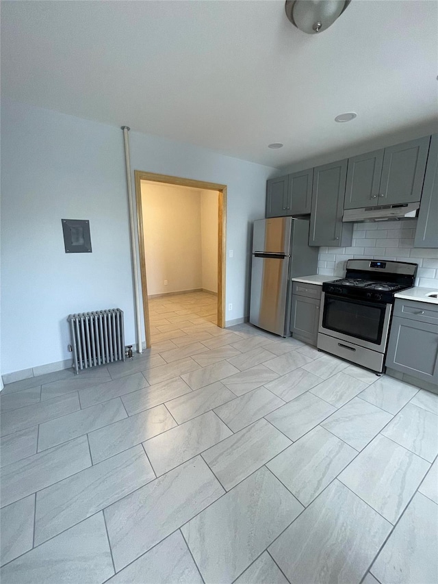 5431 Nurge Ave, Maspeth, NY 11378 - kitchen with stainless steel appliances, gray cabinetry, radiator, under cabinet range hood, and light countertops