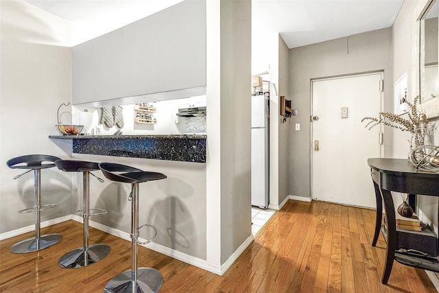 87-30 62nd Ave Unit 202, Rego Park, NY 11375 - kitchen featuring freestanding refrigerator, light wood-type flooring, baseboards, and a kitchen bar