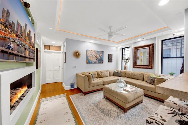 1185 Anderson Ave Unit 1F, Bronx, NY 10452 - living area with a tray ceiling, a lit fireplace, a ceiling fan, wood finished floors, and baseboards