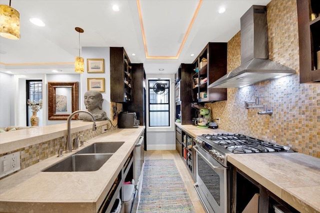 1185 Anderson Ave Unit 1F, Bronx, NY 10452 - kitchen featuring stainless steel gas stove, a sink, wall chimney range hood, decorative backsplash, and hanging light fixtures