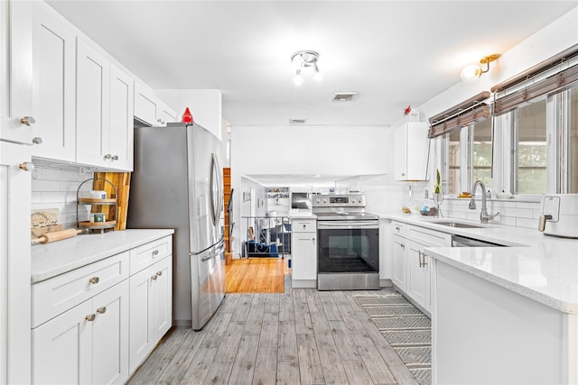 63 Wright Blvd, Hopewell Junction, NY 12533 - kitchen with appliances with stainless steel finishes, a sink, light wood-style flooring, white cabinets, and decorative backsplash