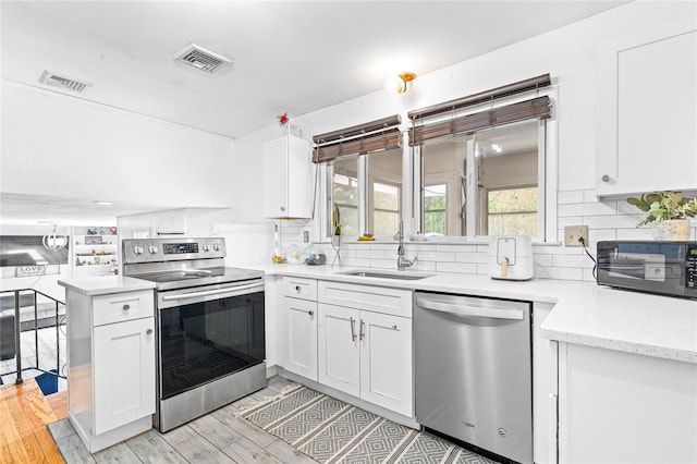 63 Wright Blvd, Hopewell Junction, NY 12533 - kitchen featuring appliances with stainless steel finishes, a sink, white cabinetry, tasteful backsplash, and light wood-type flooring