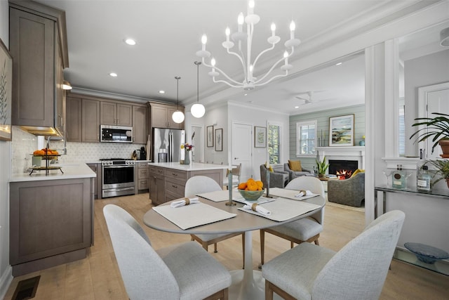 6 Livingston St, Red Hook, NY 12571 - dining area with crown molding, light wood-style flooring, a lit fireplace, a ceiling fan, and a chandelier