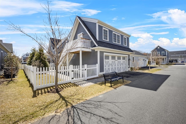 6 Livingston St, Red Hook, NY 12571 - view of front of house featuring a balcony, an attached garage, a fenced front yard, driveway, and roof with shingles