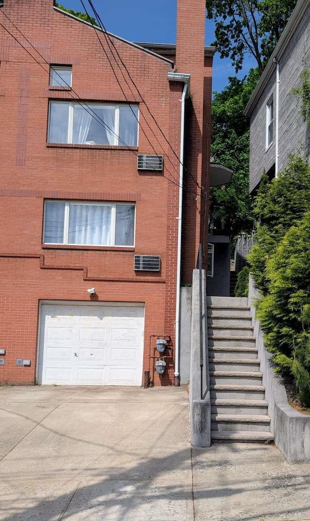 view of building exterior with a garage, driveway, and stairway