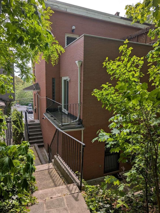 view of side of home with stairway and brick siding