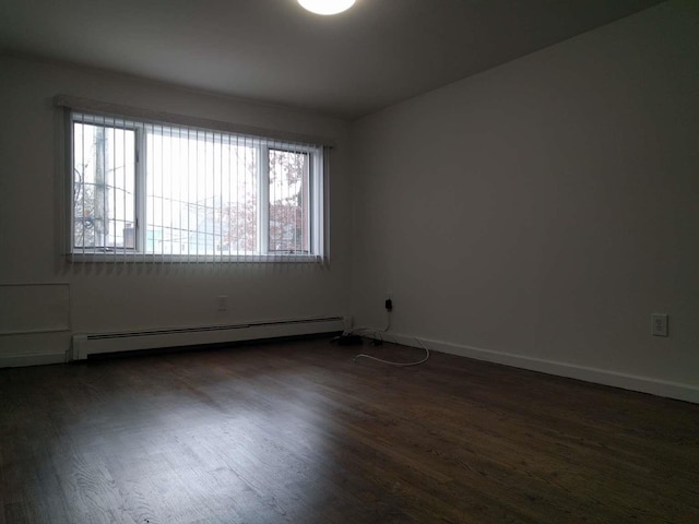 unfurnished room with baseboard heating, dark wood-style floors, and baseboards