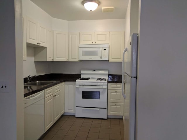 kitchen with white appliances, a sink, white cabinetry, and dark countertops