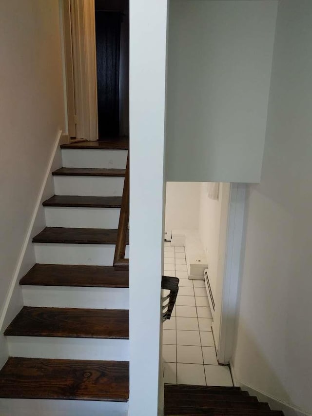 stairway featuring tile patterned floors and a baseboard heating unit