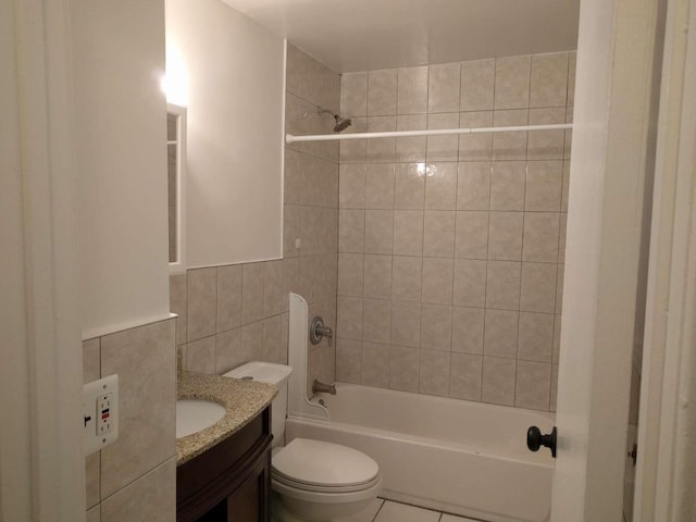 full bath with tile walls,  shower combination, toilet, and vanity