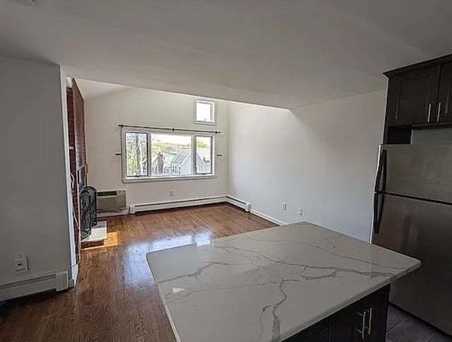 unfurnished living room with dark wood-style floors, baseboard heating, a wall unit AC, and baseboards