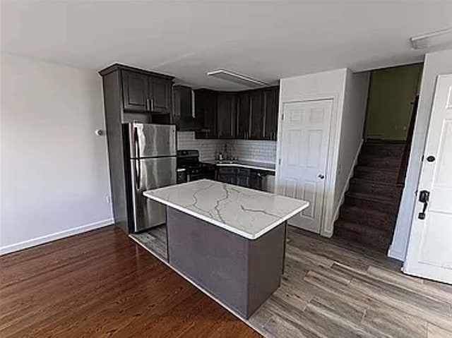 kitchen with stainless steel appliances, light stone countertops, dark wood-style floors, tasteful backsplash, and baseboards