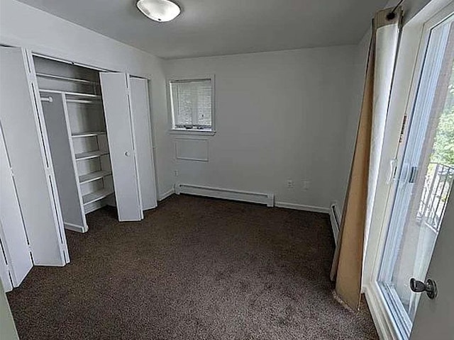 unfurnished bedroom with a baseboard heating unit and dark carpet