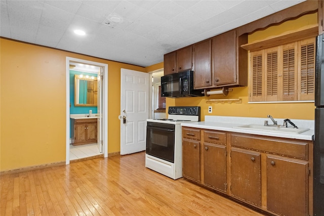 35 Fallkill Ave, Poughkeepsie, NY 12601 - kitchen with black microwave, range with electric stovetop, a sink, light countertops, and light wood-style floors