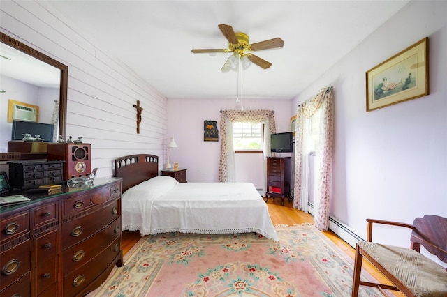 68 Forest Dr, Poughquag, NY 12570 - bedroom featuring light wood-style floors, wood walls, ceiling fan, and a baseboard heating unit