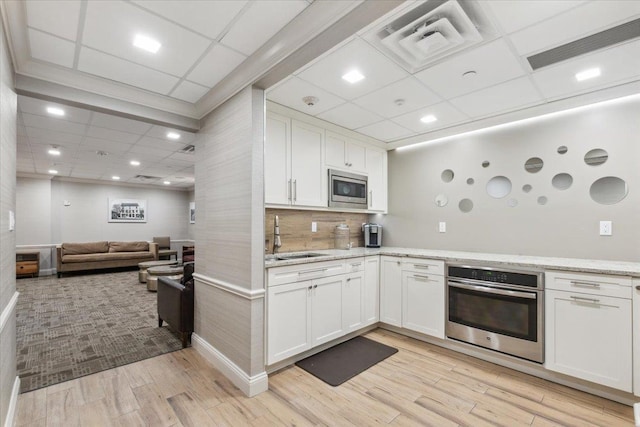 50 Columbus Ave Unit 605, Tuckahoe, NY 10707 - kitchen with stainless steel appliances, a sink, a paneled ceiling, white cabinets, and light wood finished floors