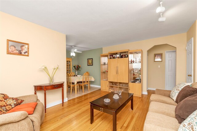 204-08 35th Ave Unit 247, Bayside, NY 11361 - living room with light wood-style flooring, arched walkways, ceiling fan, and baseboards