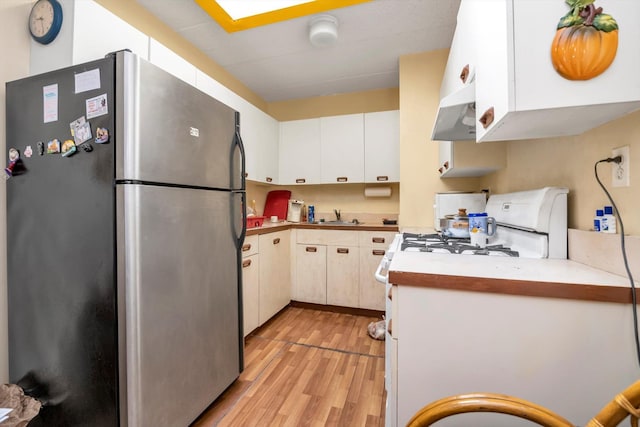 154-04 107th Ave, Jamaica, NY 11433 - kitchen featuring freestanding refrigerator, light wood-type flooring, under cabinet range hood, light countertops, and white cabinets