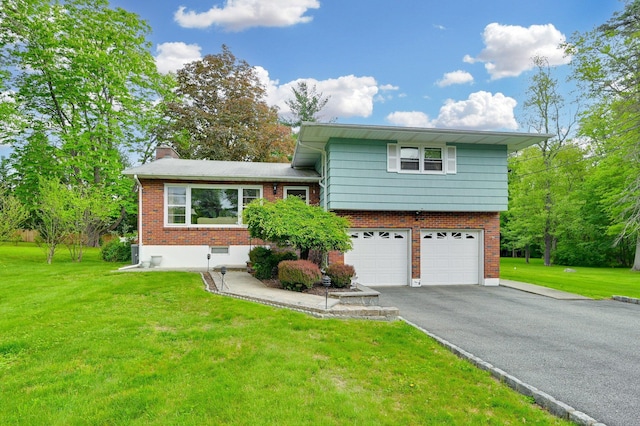 tri-level home with a garage, brick siding, driveway, a chimney, and a front yard