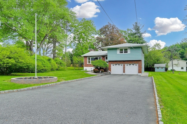 view of front of property with brick siding, driveway, an attached garage, a chimney, and a front lawn