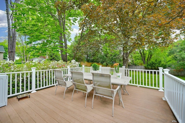 wooden terrace with outdoor dining area and view of wooded area
