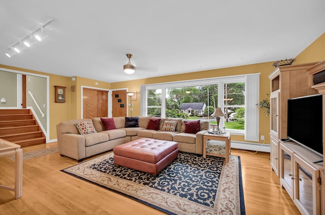 living area with track lighting, light wood-style floors, stairway, and baseboard heating