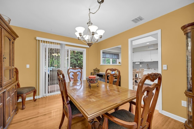 dining area featuring a chandelier, light wood-style floors, and baseboards