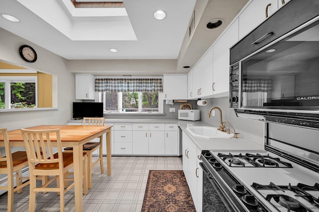 kitchen with white microwave, a tray ceiling, a sink, light countertops, and recessed lighting