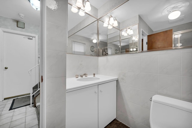 bathroom with vanity, toilet, and tile walls