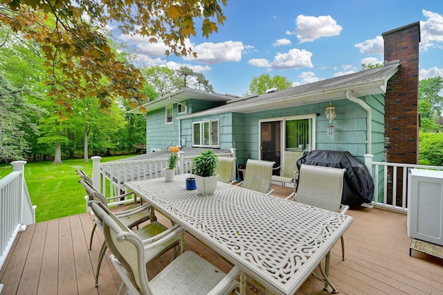 wooden terrace with outdoor dining area, a lawn, and area for grilling