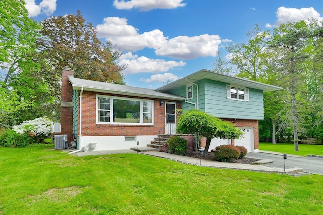 tri-level home featuring a garage, a chimney, brick siding, and a front yard