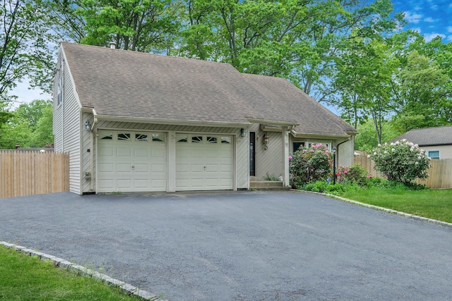 12 Grand Canyon Ln, Coram, NY 11727 - view of front facade featuring roof with shingles, fence, a garage, and asphalt driveway