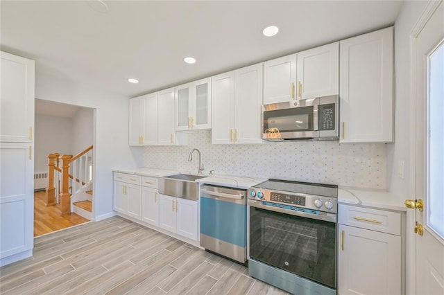1841A Decatur Ave, Bellmore, NY 11710 - kitchen featuring stainless steel appliances, radiator, a sink, light wood finished floors, and decorative backsplash