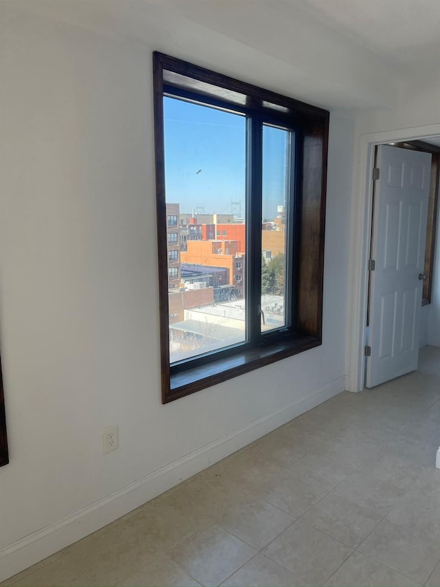 unfurnished room featuring baseboards and light tile patterned flooring