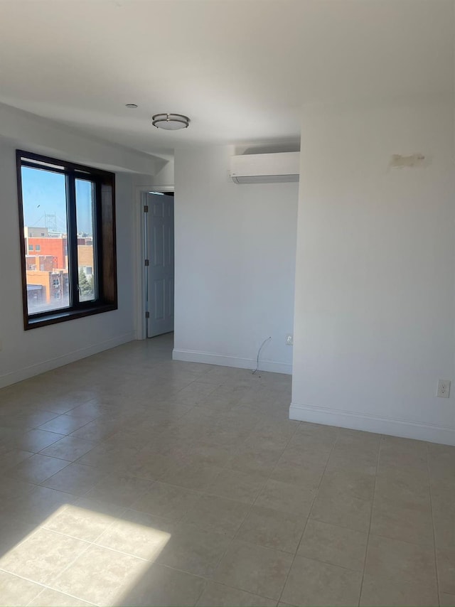 empty room featuring a wall unit AC, baseboards, and light tile patterned flooring