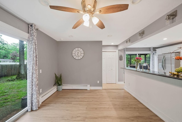 121 Tyler Ave, Miller Place, NY 11764 - unfurnished room with light wood-style flooring, baseboards, ceiling fan, a sink, and a baseboard radiator