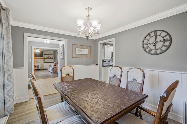 121 Tyler Ave, Miller Place, NY 11764 - dining room featuring a wainscoted wall, a chandelier, crown molding, light wood-style floors, and a ceiling fan