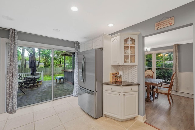121 Tyler Ave, Miller Place, NY 11764 - kitchen with stainless steel fridge, plenty of natural light, dark countertops, glass insert cabinets, and a wainscoted wall