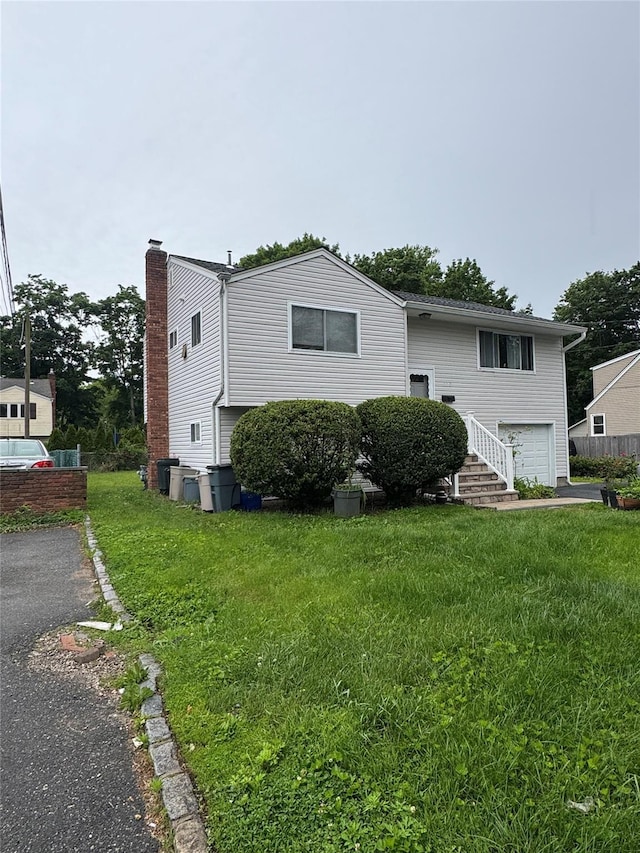 113 6th Ave, Huntington Station, NY 11746 - view of front of property with asphalt driveway, an attached garage, and a front lawn