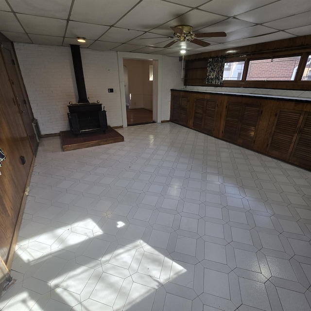 78-10 222nd St, Oakland Gardens, NY 11364 - unfurnished living room with a wood stove, a paneled ceiling, a ceiling fan, and tile patterned floors