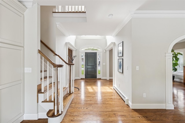 38 Savanna Cir, Mount Sinai, NY 11766 - entryway featuring a baseboard radiator, light wood finished floors, arched walkways, ornamental molding, and stairway