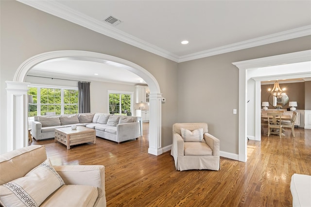 38 Savanna Cir, Mount Sinai, NY 11766 - living room with arched walkways, decorative columns, crown molding, wood finished floors, and a chandelier