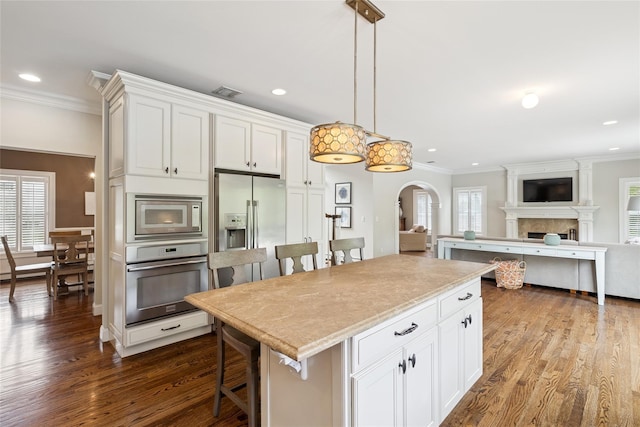 38 Savanna Cir, Mount Sinai, NY 11766 - kitchen featuring stainless steel appliances, crown molding, a breakfast bar area, plenty of natural light, and dark wood finished floors