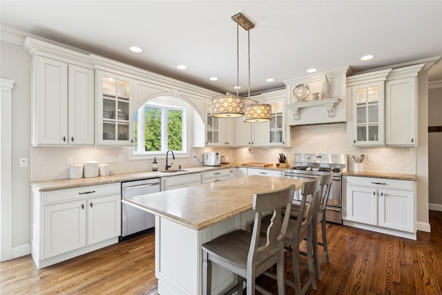 38 Savanna Cir, Mount Sinai, NY 11766 - kitchen with appliances with stainless steel finishes, a sink, light countertops, dark wood-type flooring, and a center island