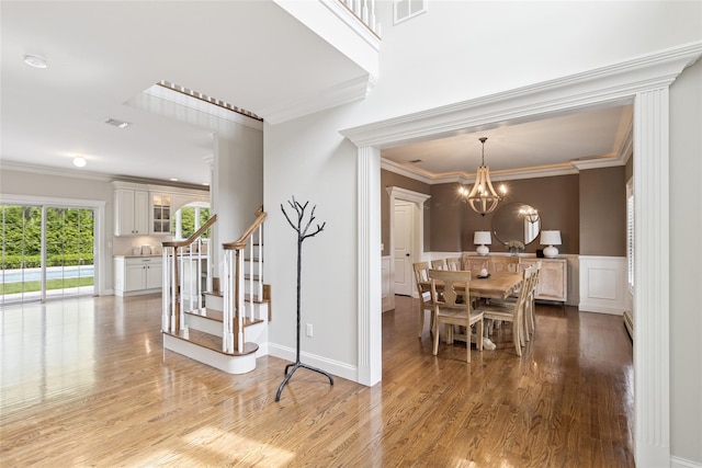 38 Savanna Cir, Mount Sinai, NY 11766 - dining room featuring ornamental molding, stairway, light wood-style floors, a chandelier, and a decorative wall