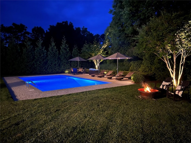 38 Savanna Cir, Mount Sinai, NY 11766 - pool at night with a fire pit, a patio, a yard, and an outdoor pool