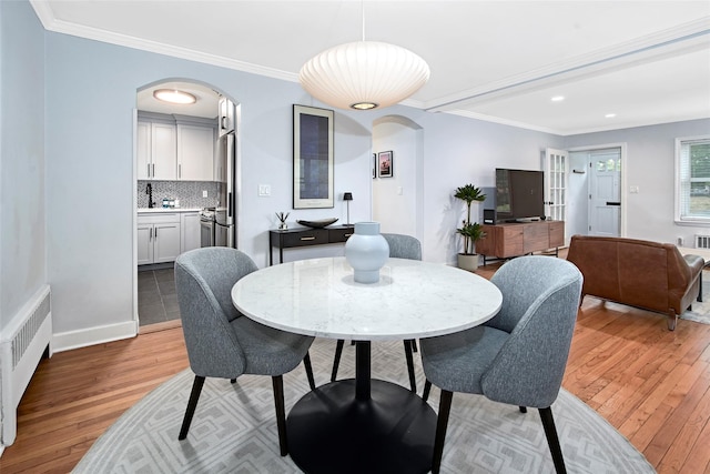4 Peck Unit 47A, Rye, NY 10580 - dining space featuring arched walkways, light wood-style flooring, radiator heating unit, crown molding, and recessed lighting