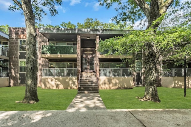 12427 Flatlands Ave Unit 1A, Brooklyn, NY 11208 - view of front facade with brick siding, a front yard, stairway, and a balcony