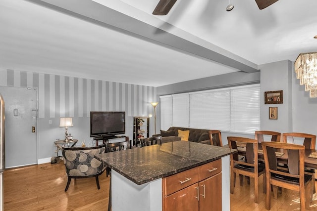 12427 Flatlands Ave Unit 1A, Brooklyn, NY 11208 - kitchen with light wood-style flooring, dark stone countertops, ceiling fan, brown cabinets, and a kitchen island